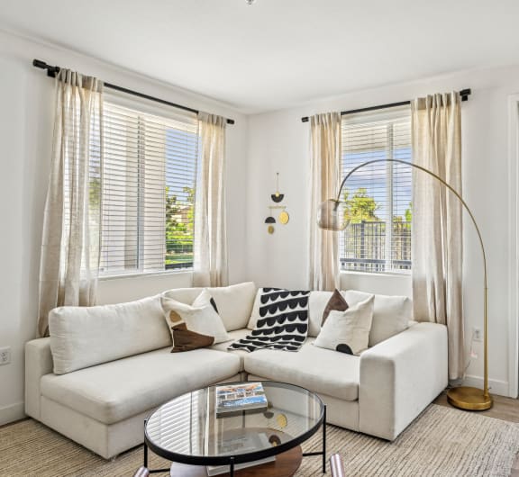 a living room with a white couch and a glass coffee table a living room with a white couch and a glass coffee table at The Venue at Orange Apartments, California
