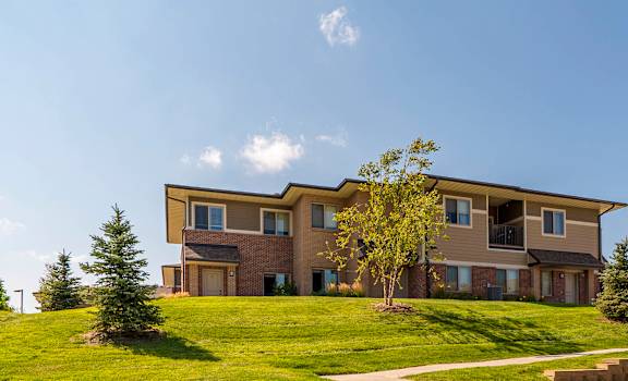 Villas style apartment building on top of a grassy landscaped hill