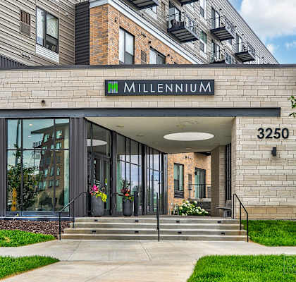 the front of the millenium building with stairs and grass
