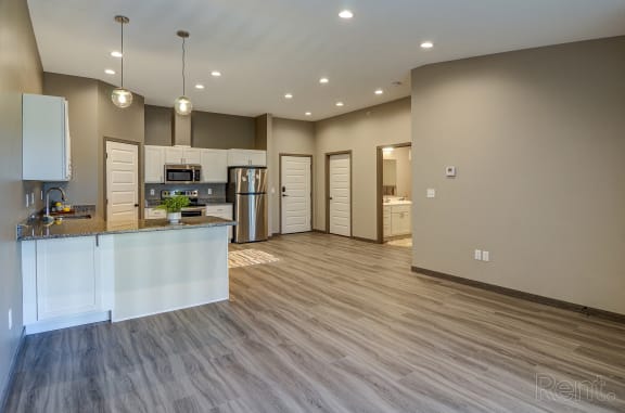 an open kitchen and living room with a kitchen island and a refrigerator