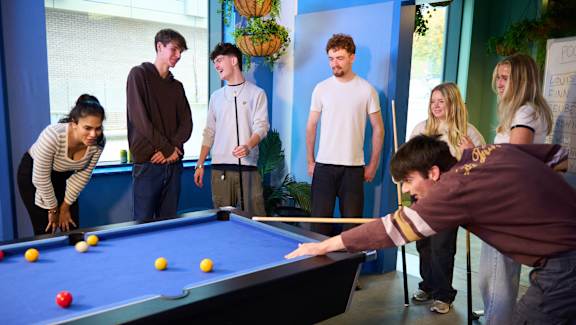 A group of people playing pool in a room.
