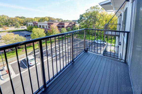 a balcony with a view of a parking lot and trees