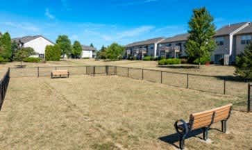 A park with a bench and a fence in front of a row of houses.