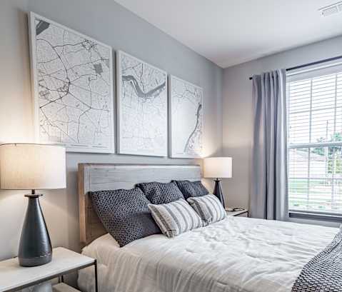 a bedroom with a large bed and a window at The Louis Apartment Flats, Louisville, KY