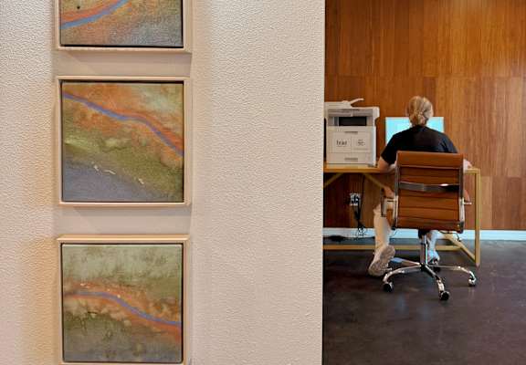 Three landscape paintings are hanging on a white wall.