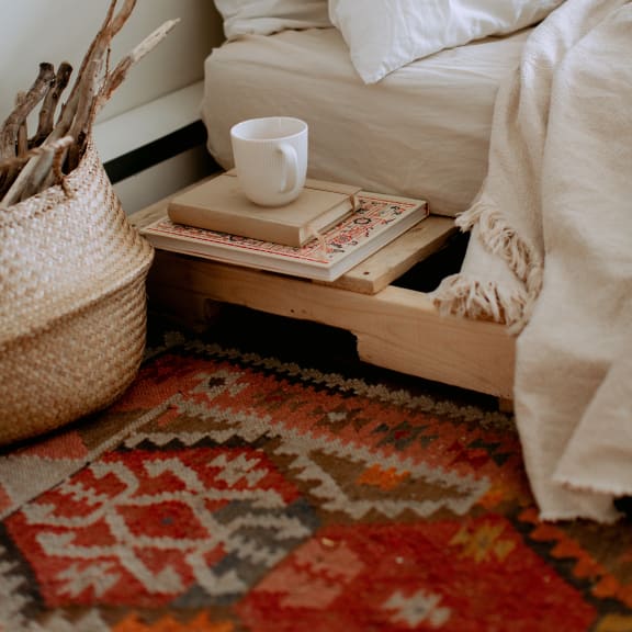 a tray with books and a cup of coffee on it next to a bed