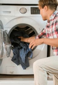 a man putting laundry in an in-home washing machine