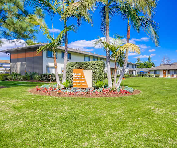 a building with palm trees and a sign in the grass