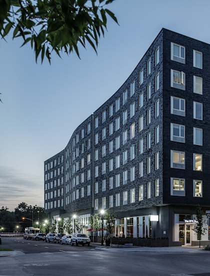 A modern multi-story building with a parking lot in front. at The Fowler Apartments, Boise, ID