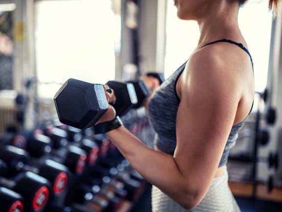 A woman is lifting a dumbbell in a gym.