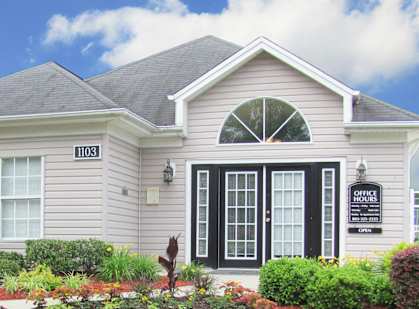 the front of a house with a lawn and a sidewalk