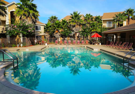 A swimming pool surrounded by palm trees and lounge chairs at San Marco Apartments, Ormond Beach, FL, 32174