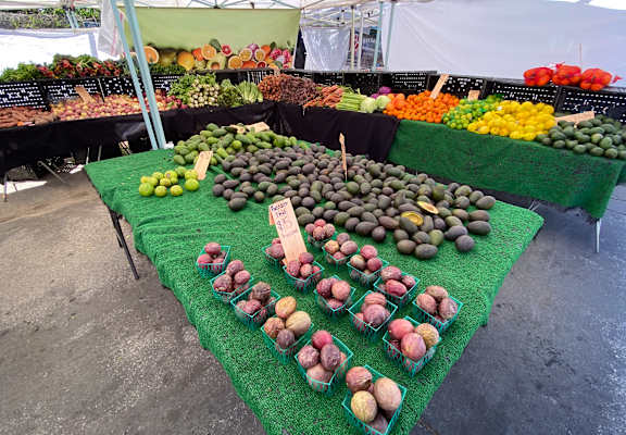 A fruit stand with a green table cloth and a variety of fruits on display.