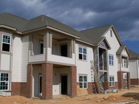 A row of houses under construction with a clear blue sky.