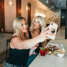 Two women taking a selfie at a restaurant.