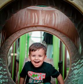 A young boy is playing on a slide at a playground.