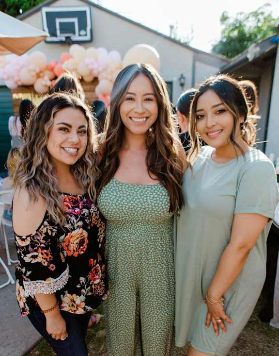 Three women are standing together and smiling for the camera.