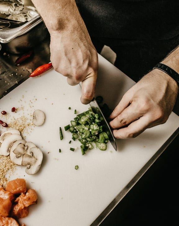 a man cutting up vegetables on a cutting board
