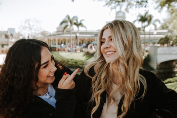 two women standing next to each other in a park