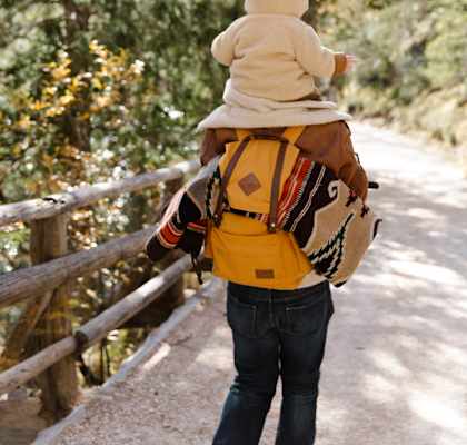 a man with a yellow backpack and a small child on his shoulders