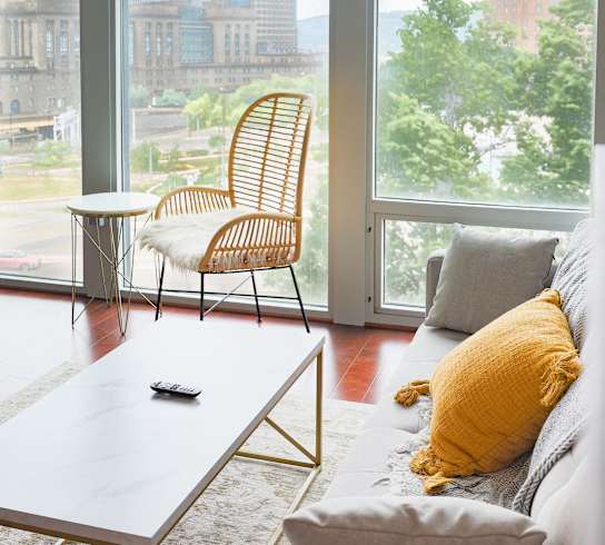 A living room with a grey couch, a white coffee table, and a yellow pillow. at The Washington at Chatham, Pittsburgh Pennsylvania
