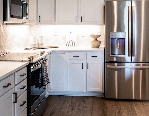 a white kitchen with stainless steel appliances and white cabinets