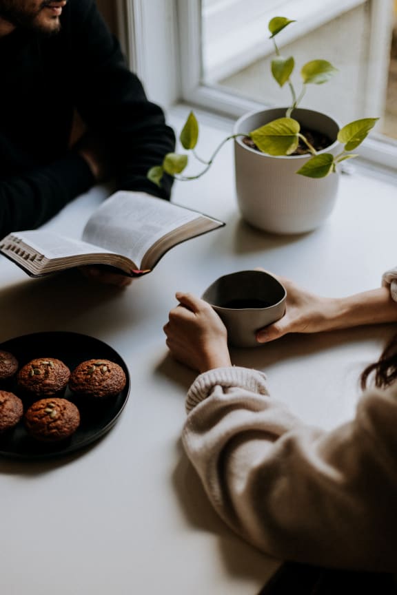 two people sitting at a table with a plate of muffins