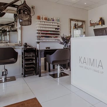 a salon with a white sign in front of a hair salon with chairs