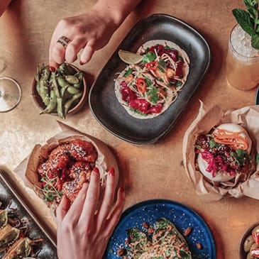 a table topped with plates of food and people eating food