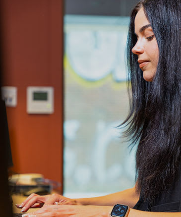 a woman with long black hair working on a computer
