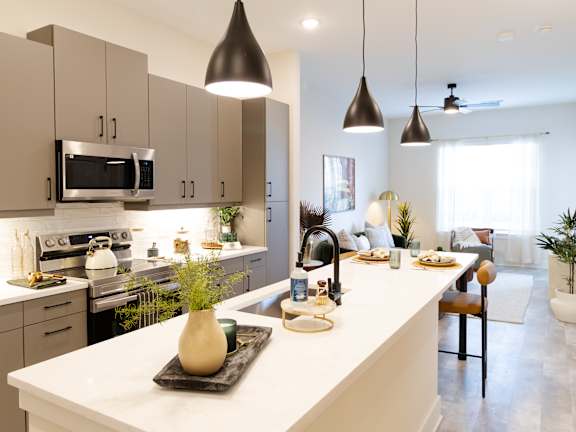 A modern kitchen with a long black island and wooden chairs.