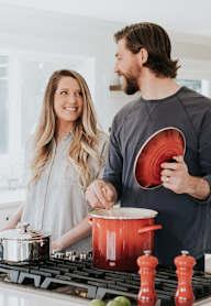 A man and woman are cooking together in a kitchen.