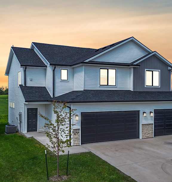 A house with a grey roof and two garages.