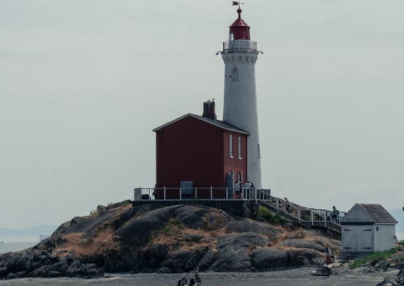 a lighthouse on a rock in front of a body of water