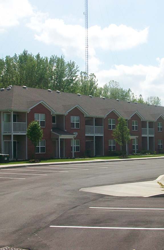 A parking lot in front of a building with a tall antenna in the background.