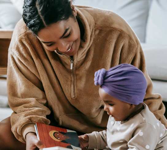 a mother reading a book to her child on the floor