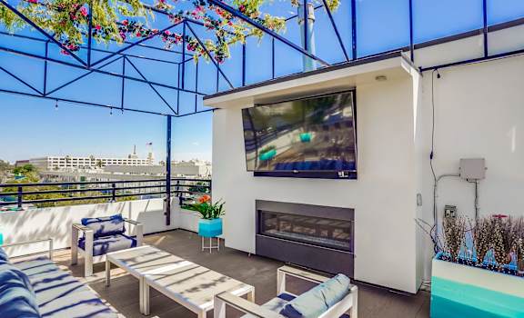 an outdoor patio with couches and a fire place and a flat screen tv