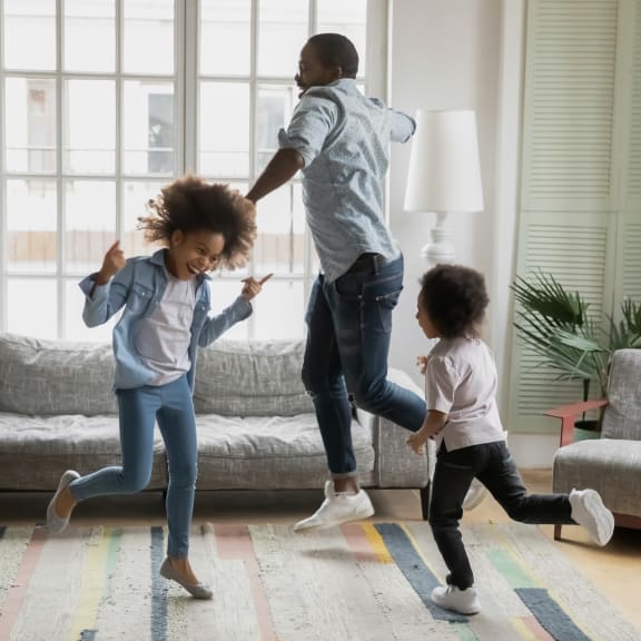 a father and two children jumping in a living room at Addison Ranch Apartments, Petaluma, 94954