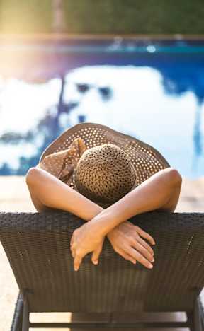 A woman in a hat is sitting on a chair by the pool.at Prairie Encore, Missouri