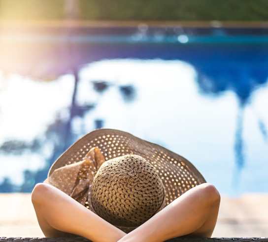 Woman in a hat is sitting on a chair by the pool at Plaza at Pinnacle Hills, Rogers