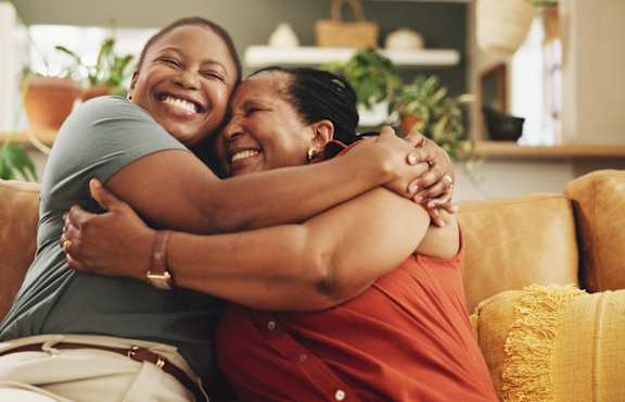 Two people hugging each other on a couch.