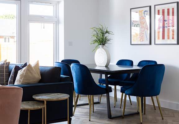 a dining room with a table with blue chairs and a vase with a plant