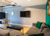 Thumbnail 2 of 8 - a living room with a couch and a table and a television