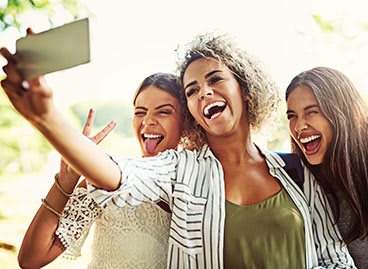 three women taking a picture of themselves with a cell phone