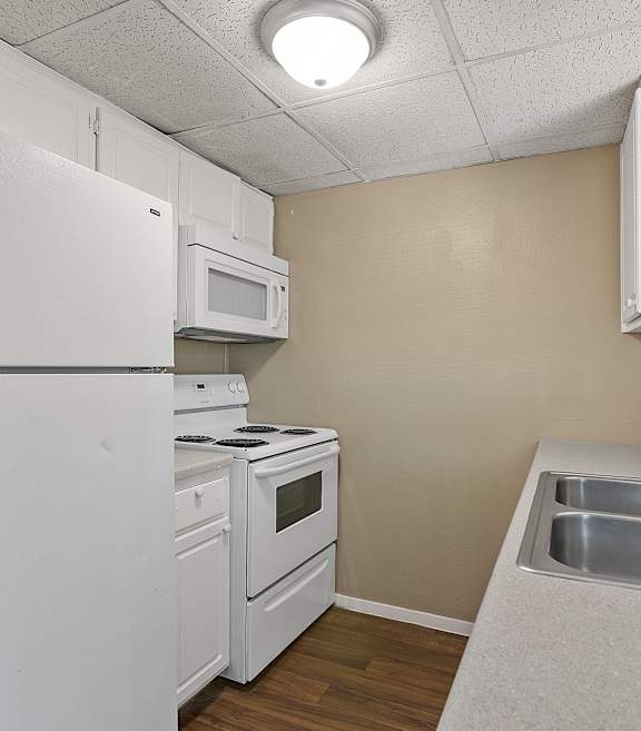 A small kitchen with white appliances and a white refrigerator.