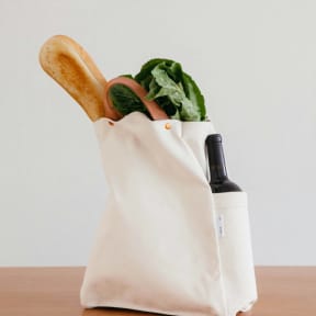 a white bag with a wooden spoon and a bottle of wine