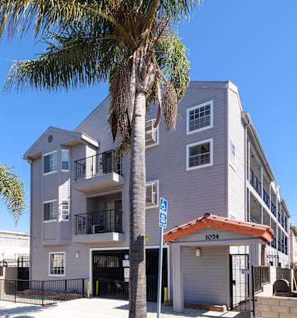 A palm tree stands in front of a two-story building with a garage.