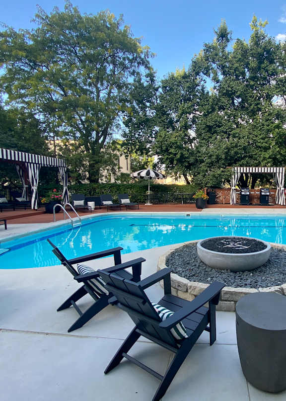 A pool with four chairs around a fire pit.