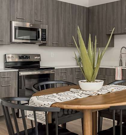 a kitchen with stainless steel appliances and a wooden table with chairs