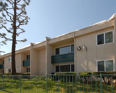 an apartment building with a fence and a tree in front of it